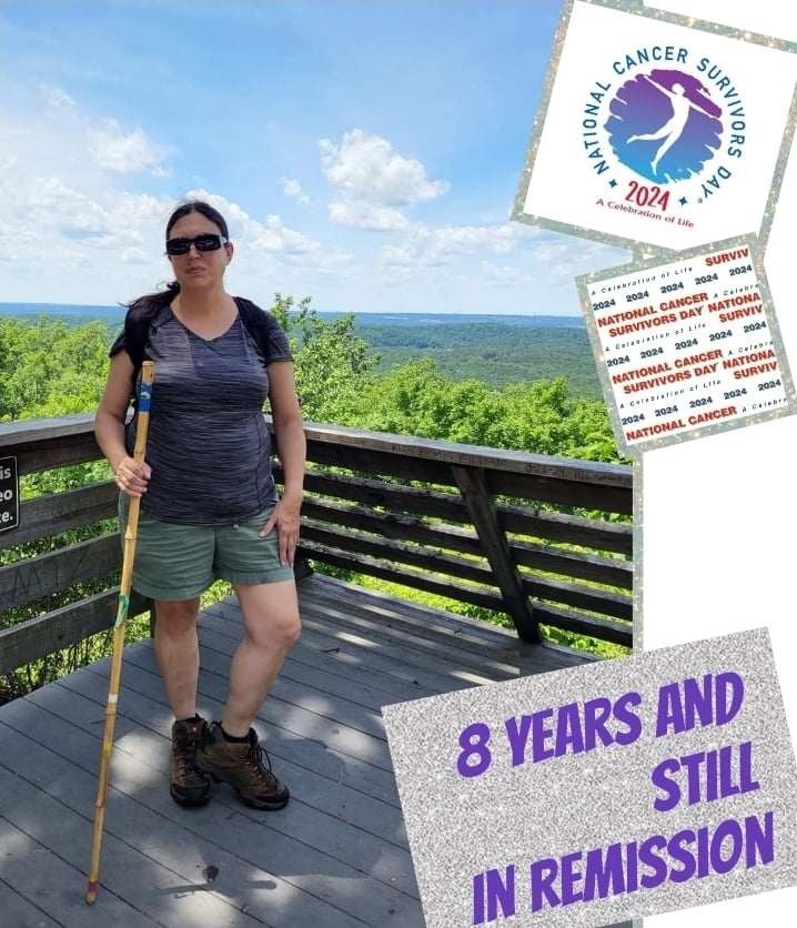A woman stands on a wooden overlook with a scenic green landscape behind her, celebrating 8 years in remission from cancer.