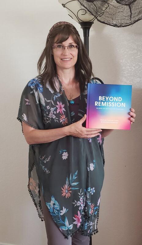 Author holding the book "Beyond Remission" in a floral shawl, showcasing her work on healing and resilience. The image highlights her passion and commitment to the topic.